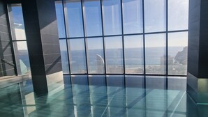 Un interior moderno con ventanas amplias que ofrecen vistas a una ciudad costera.
