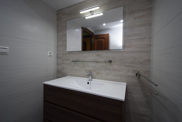 A bathroom with a white sink, a mirror, and a wooden vanity. - SAN Pedro 3 Bedrooms (Benidorm)