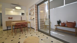 Een modern interieur met een eethoek, een bank en een schuifpui naar een balkon.