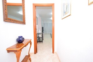 A hallway with a wooden door leading to a room, a mirror on the wall, and a small table with a vase. - Lidersol 11f2 in Benidorm (Benidorm)