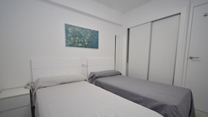 A room with two single beds, a nightstand, a wardrobe, and a painting on the wall. - Mariscal 4 4C in Benidorm (Benidorm)