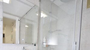 A modern bathroom with a glass-enclosed shower, a white vanity with a mirror, and a tiled wall. - Mariscal 4 4C in Benidorm (Benidorm)