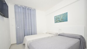 A hotel room with two beds, a flat-screen TV mounted on the wall, and a painting above the beds. - Mariscal 4 4C in Benidorm (Benidorm)
