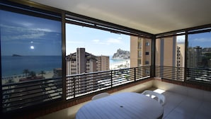 A balcony with a table and chairs, overlooking a beach and buildings. - Castelmar 8B in Benidorm (Benidorm)