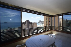 A balcony with a table and chairs, overlooking a beach and buildings. - Castelmar 8B in Benidorm (Benidorm)