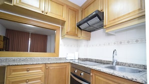 A kitchen with wooden cabinets, a granite countertop, a stainless steel sink, and a built-in oven. - Castelmar 8B in Benidorm (Benidorm)