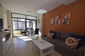 Ein modernes Wohnzimmer mit grauem Sofa, weißem Couchtisch und einem Essbereich mit Tisch und Stühlen.