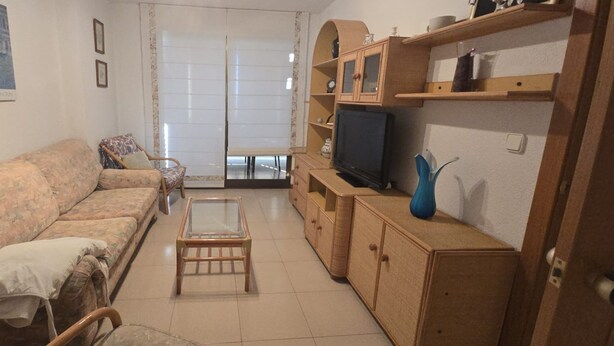 A living room with a sofa, a glass coffee table, and a TV on a wooden cabinet. - Castelmar 1C in Benidorm (Benidorm)