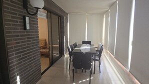 A balcony with a table and chairs, a brick wall, and a sliding glass door leading to an interior space. - Castelmar 1C in Benidorm (Benidorm)