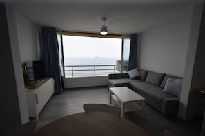 A modern living room with a sofa, a coffee table, and a TV on a cabinet. A large window offers a view of the sea. - Coblanca 1 21-3 in Benidorm (Benidorm)