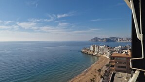 Un paysage urbain côtier avec une plage, des bâtiments et une montagne à l’horizon.