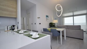 Et moderne køkken med spiseplads, en sofa og et bord dækket til fire med en grøn dug.