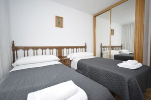 Une chambre d’hôtel avec deux lits, une tête de lit en bois, une table de chevet et un grand miroir.