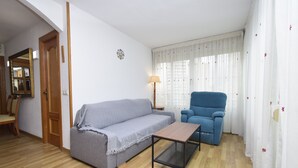 Una sala de estar con un sofá gris, un sillón azul, una mesa de centro de madera y una lámpara.