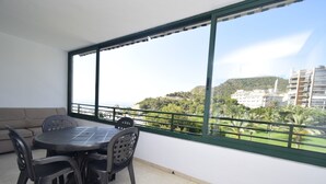 Un balcon avec une table et des chaises, donnant sur un paysage urbain et une végétation luxuriante.