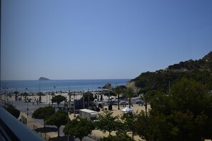 Une vue sur la côte, avec une plage, des véhicules garés et une île au loin.