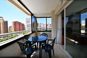 A balcony with a table and chairs, a glass door, and a view of buildings. - Parque Europa 5B1 in Benidorm (Benidorm)