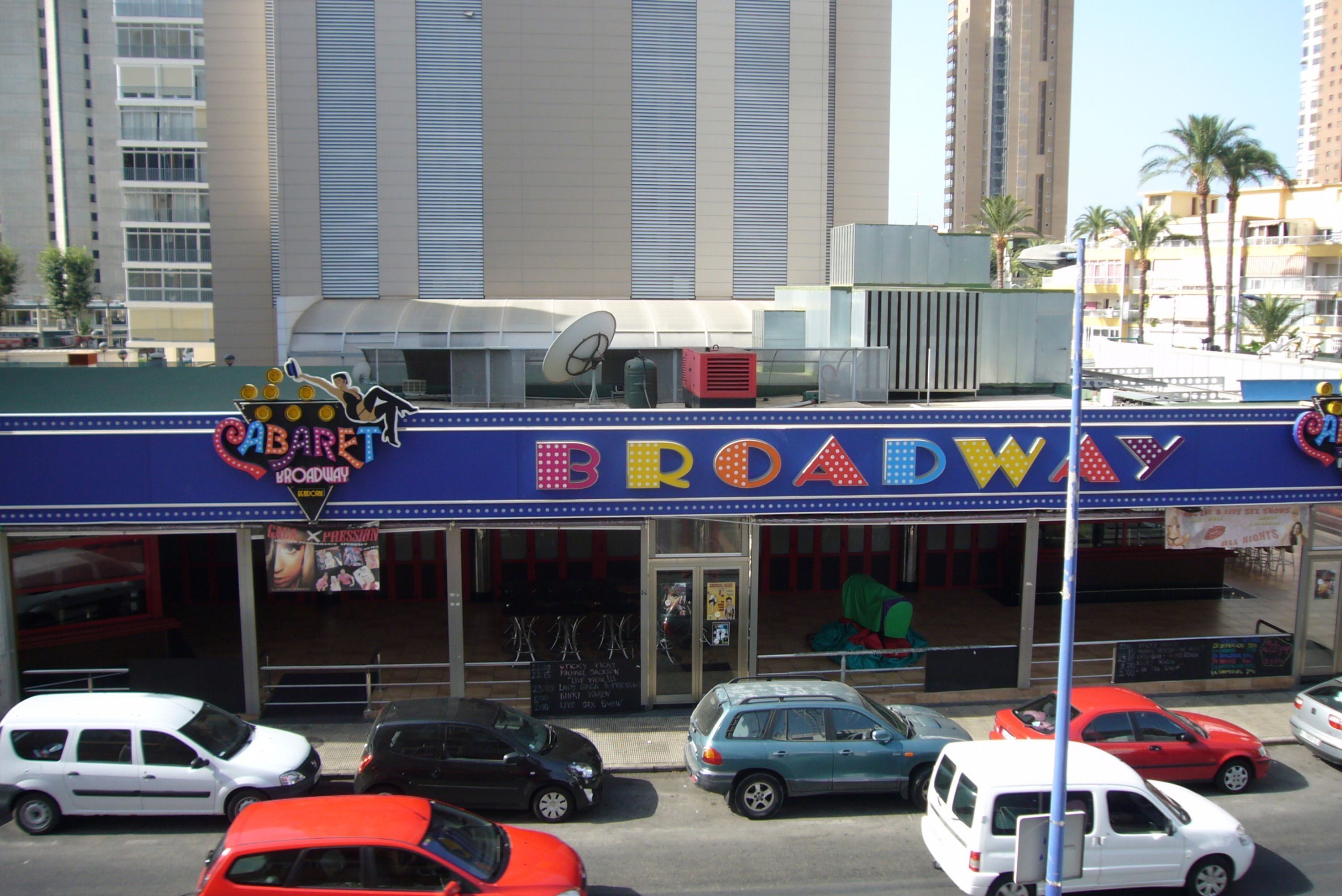 Un edificio con un letrero que dice "BROADWAY" y una antena parabólica en el techo.