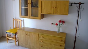 A room with a wooden cabinet, a chair, and a vase with flowers. - Oce3 2A in Benidorm With 2 Bedrooms and 1 Bathrooms (Benidorm)