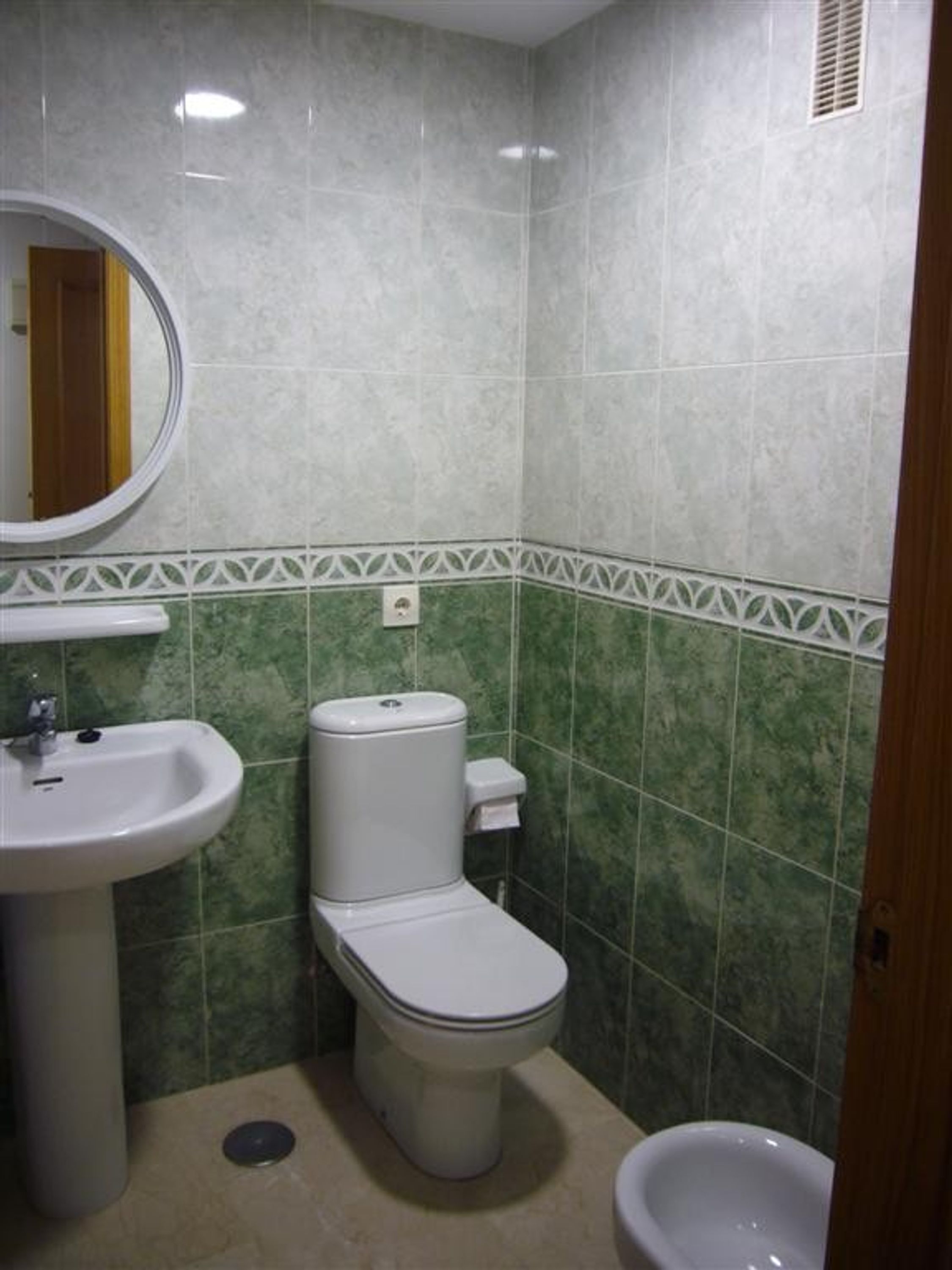 A bathroom with a toilet, sink, and bidet.
