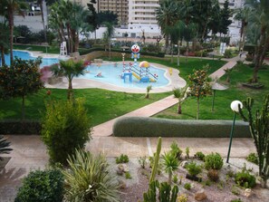 A pool area with a water slide, palm trees, and a cactus garden. - Gemelos 22 13c3 in Benidorm (Benidorm)