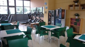 A fitness center with exercise equipment, green chairs, and a vending machine. - Gemelos 22 13c3 in Benidorm (Benidorm)