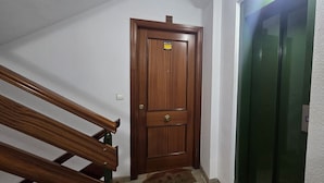 Eine Holztür mit einem Schild, eine grüne Schiebetür und eine Treppe mit hölzernen Geländern.