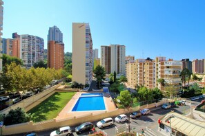 A residential area with a swimming pool, multiple apartment buildings, and a street with parked cars. - Cadiz 4B in Benidorm (Benidorm)