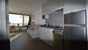 Eine moderne Küche mit integriertem Mikrowellenherd, einem Edelstahlkühlschrank und einem Geschirrspüler. Es gibt eine Essecke mit Tisch und Stühlen sowie ein Sofa.