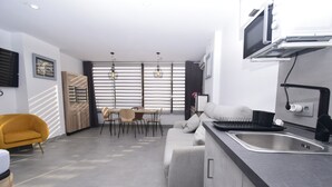 A modern kitchen with a dining area, a sofa, and a TV mounted above the counter. - Coblanca 29 - T2 16-5 (Benidorm)