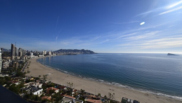 A coastal cityscape with a beach, buildings, and a mountain in the distance. - Coblanca 29 - T2 16-5 (Benidorm)