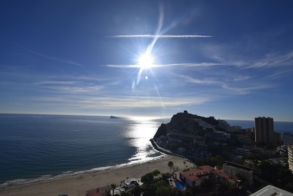 A coastal cityscape with a beach, buildings, and a prominent cliff.