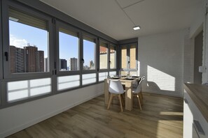 A modern kitchen with large windows, a dining table with chairs, and a view of the cityscape. - Lidersol 14g2 in Benidorm (Benidorm)