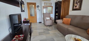 A living room with a sofa, a television, a coffee table, a bookshelf, and a door. - Cachirulo 6D in Benidorm (Benidorm)