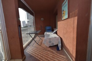 Varanda com mesa, cadeiras e uma pequena mesa coberta por um tecido estampado.