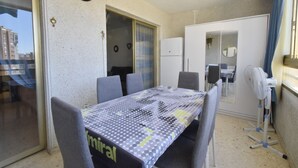 A balcony with a dining table, chairs, a refrigerator, and a fan. - Mariscal 6 8B in Benidorm (Benidorm)