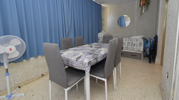 A dining area with a table, chairs, a fan, and a blue curtain. - Mariscal 6 8B in Benidorm (Benidorm)