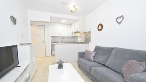 A modern living room with a grey sofa, white coffee table, and a flat-screen TV on a white cabinet. - Mariscal 6 8B in Benidorm (Benidorm)