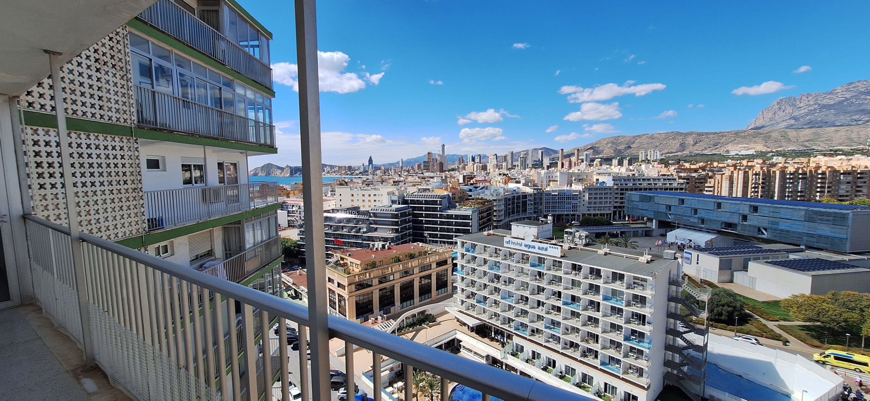 Un hotel amb diverses plantes, balcons i vista a la ciutat i a les muntanyes.
