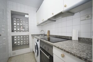 A kitchen with a built-in oven, a washing machine, and a countertop with a sink. - Flecha 13D 3 Dormitorios (Benidorm)