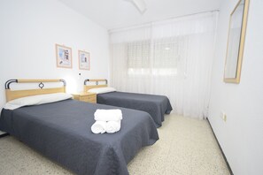A hotel room with two single beds, a nightstand, a mirror, and a window with sheer curtains. - Flecha 13D 3 Dormitorios (Benidorm)