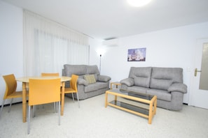 A living room with a grey sofa, yellow chairs, a glass coffee table, and a white floor. - Flecha 13D 3 Dormitorios (Benidorm)