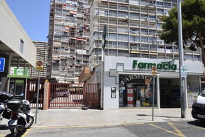 Eine Apotheke mit geschlossenem Eingangsbereich, ein Motorrad parkt vor der Tür, und im Hintergrund ein mehrstöckiges Gebäude.