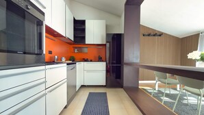 A modern kitchen with white cabinets, a black oven, and a red accent wall. - Il Terrazzo di Betta With Garage 15 min to Duomo (Milan)