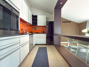 A modern kitchen with white cabinets, a black oven, and a red accent wall. - Il Terrazzo di Betta With Garage 15 min to Duomo (Milan)