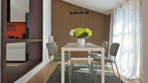 A modern dining area with a white table, green chairs, and a vase of flowers. - Il Terrazzo di Betta With Garage 15 min to Duomo (Milan)