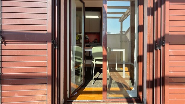 A sliding glass door leading to a dining area with a table and chairs. - Il Terrazzo di Betta With Garage 15 min to Duomo (Milan)