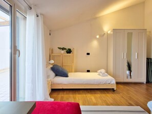 Une chambre à coucher comprenant un lit, une armoire, une table de chevet, une lampe et une fenêtre avec des rideaux.
