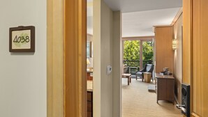 A hallway leading to a living area with a wooden door, a number sign, and a view of the outdoor patio.