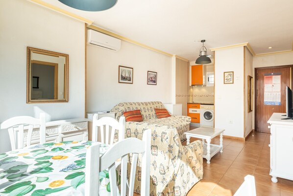 Ein Zimmer mit einem Bett, einem Schreibtisch, einem Stuhl, einer Waschmaschine und einem Spiegel.